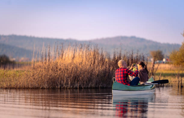 Travelers in canoes on Lake Cerkniško Excursionists enjoy and have fun exploring Cerkni Lake in good weather and at sunset.They observe animals and nature through binoculars and take selfies in the sunset. cerknica lake stock pictures, royalty-free photos & images