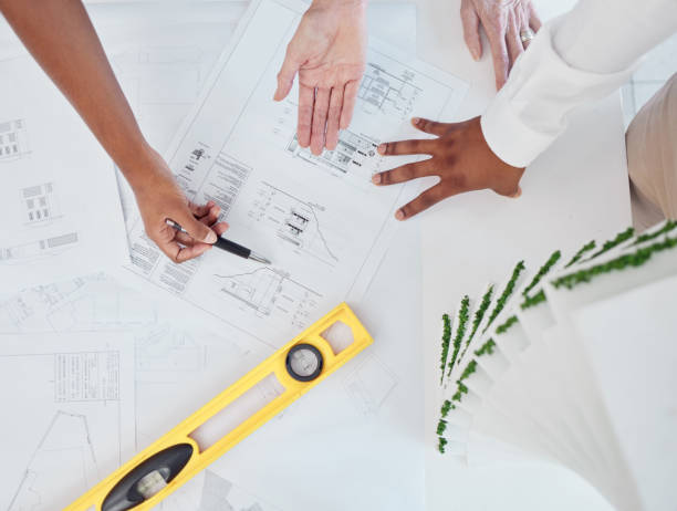 istock Architect, hands and construction planning for building industry in team discussion or meeting on the table. Hand of business people in architecture or industrial design for project or model plan 1453987142