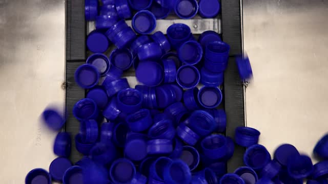 Blue plastic bottle caps moving up the conveyor belt at the beverage processing factory