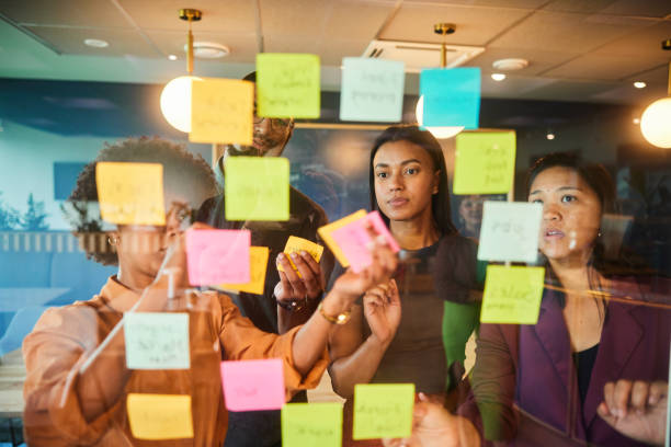 istock Diverse businesspeople brainstorming together with adhesive notes on an office window 1453987208
