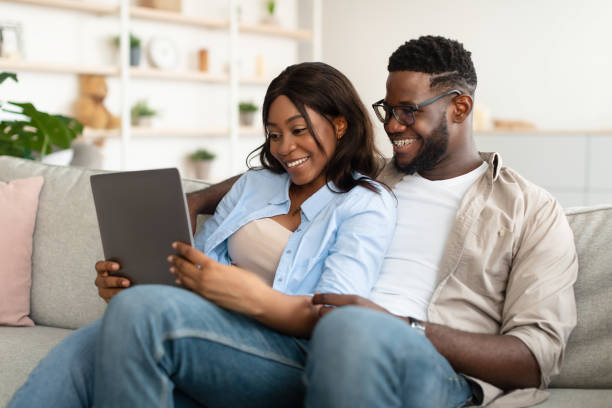 istock African american couple sitting on couch, using tablet 1453987767