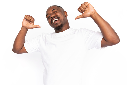 Cheerful African American man pointing at himself. Portrait of happy young male model with short hair in white T-shirt looking at camera, winking and smiling. Self-assurance, success concept