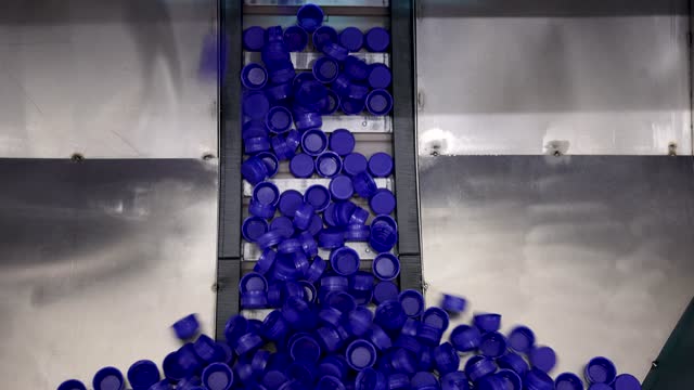 Blue plastic bottle caps moving up the conveyor belt at the beverage processing factory