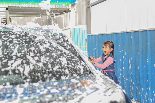 Asian girls learning how to wash a car for their father. Chinese people customarily clean up before Chinese New Year.