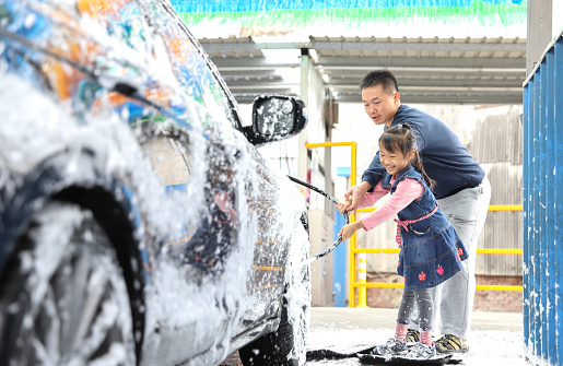 Asian girls learning how to wash a car for their father. Chinese people customarily clean up before Chinese New Year.