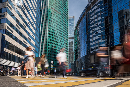 People traffic blurred in motion at the crosswalk at modern office business quarter
