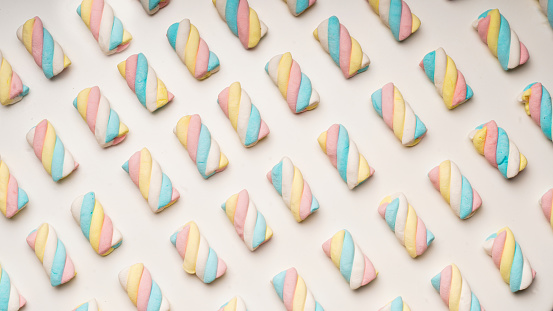 A top view of colorful marshmallows on a pink background