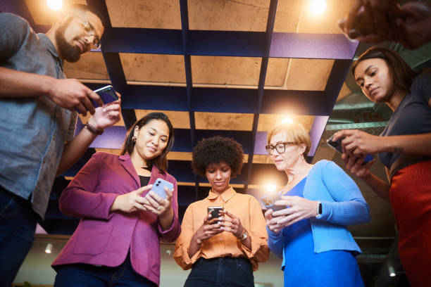 istock Smiling businesspeople checking their phones while standing in an office 1453997284