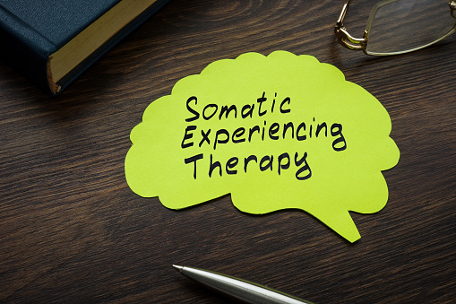 Somatic experiencing therapy sign on a page with brain shape.