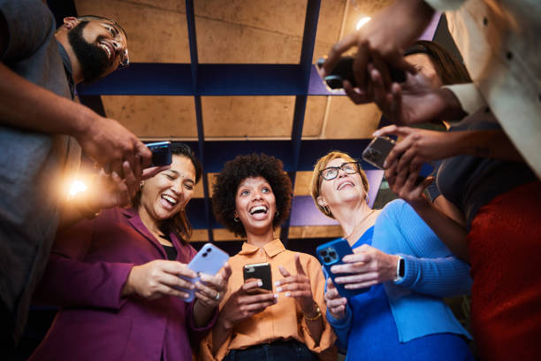 istock Laughing businesspeople checking their phones while standing in an office 1453997384
