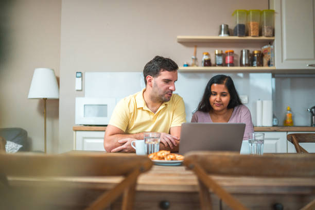 istock Diverse Couple Entertaining Themselves In A Kitchen Using Laptop 1453997588