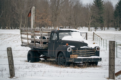 Brant, United States – December 27, 2022: A closeup shot of an old Chevy 400 stake truck parked on the side of the road on a winter day