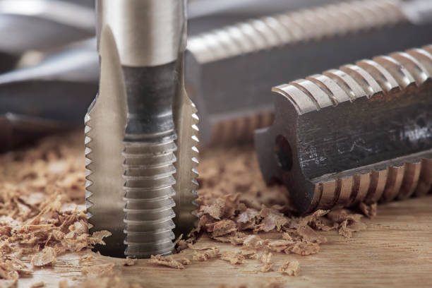 istock Thread tap drill cutting hole in wooden plate. Working cutter. 1453998239