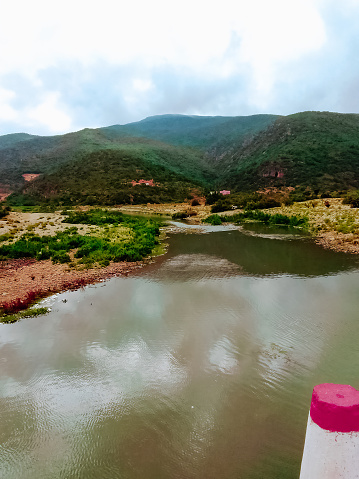 Landscape of a small lake in front of a mountain with cloudy sky