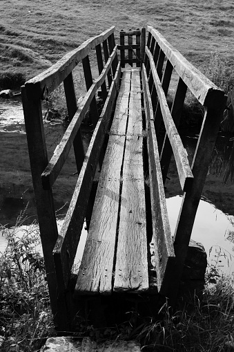 Narrow wooden bridge over trout fishing river in England, Summer.