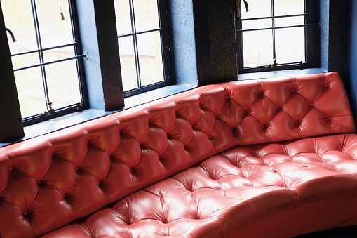 Vintage, retro, mid-century red leather bench sofa in living room, Winter.