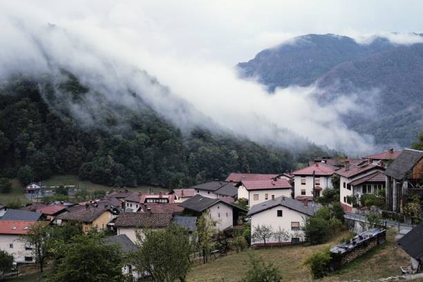 istock Clouds coming down a mountain onto a village 1453999526