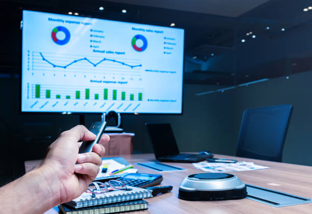 istock Businessman hand hold remote control slide with presentation on display laptop and television 1454000678