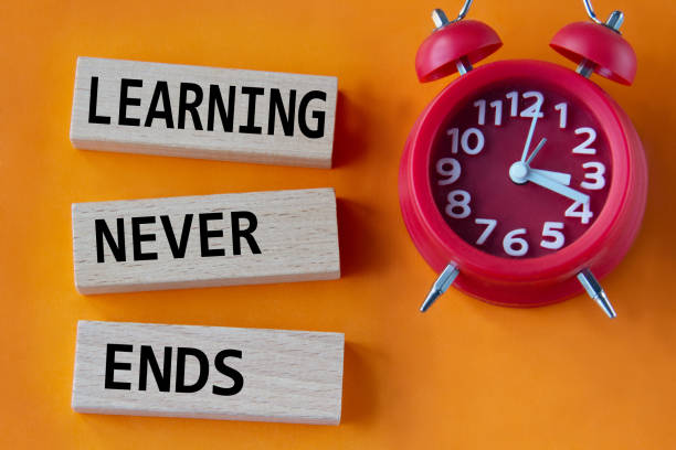 istock LEARNING NEVER ENDS - words on wooden blocks on orange background with red clock 1454002645