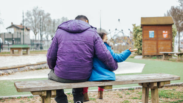 istock Father with his daughter sitting on a park bench 1454004639