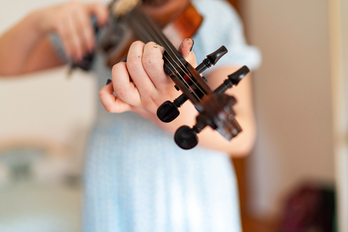 Unrecognizable teenage girl playing violin at home