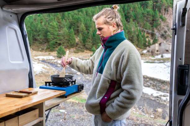 istock Teenage boy cooking outdoors in a van 1454007523