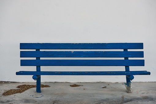 A closeup shot of a blue wooden bench against a white wall in Santorini, Greece