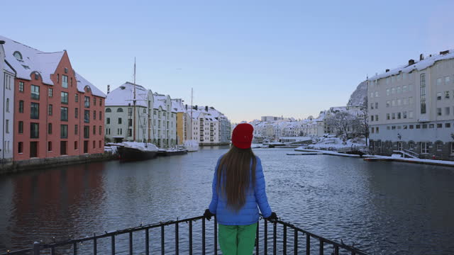 Rear view of woman contemplating a view of Alesund city in snow in Norway