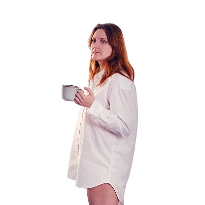 An adult woman at the window with a cup of coffee in her hands, isolated on a white background. Concept of coronavirus quarantine and home isolation
