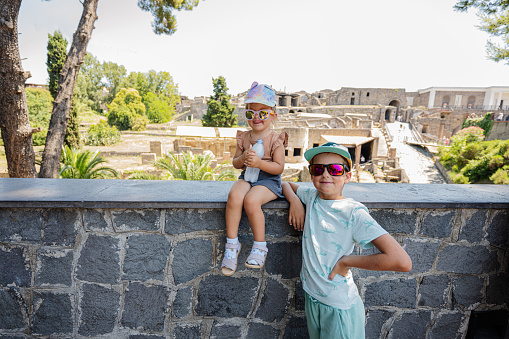 Baby girl tourist with brother against panoramic view of the ancient city of Pompeii.