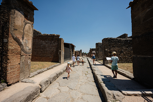 Family tourist walking at Pompeii ancient city, Italy.