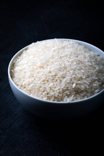 istock White bowl containing uncooked white rice against a black background. 1454008979