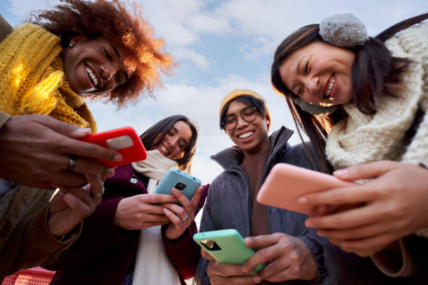 istock Low angle view of a smiling group of young people using mobile phone. Technology connection addicted 1454009339