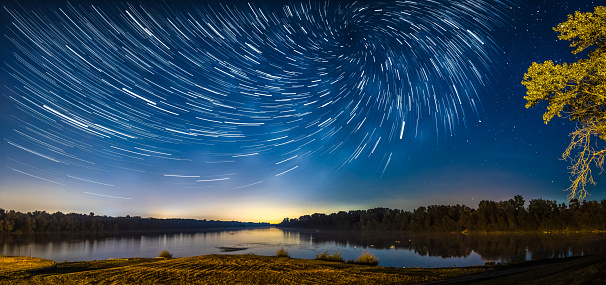 A panorama view of a beautiful forest near the lake at a starry night in Germany