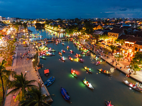 Hoi An at dusk with boats cruising on river side with lantern