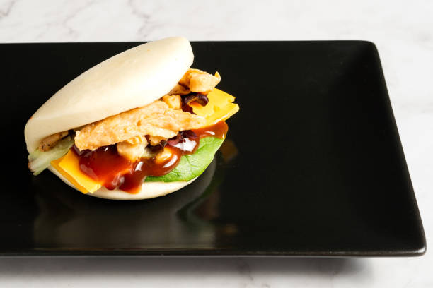 Bao buns stuffed with chicken and vegetables served on a black plate. Typical asian food stock photo