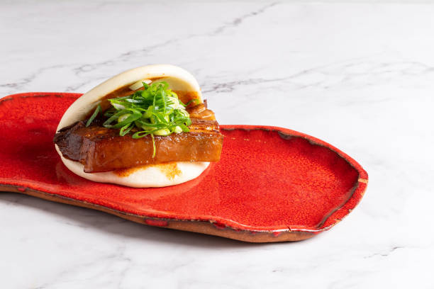 Bao buns stuffed with chicken and vegetables served on a red plate. Typical asian food stock photo