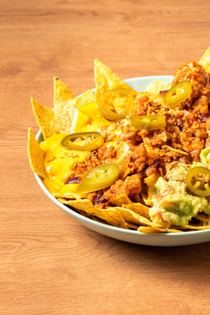 Corn chips nachos with fried minced meat and guacamole on wooden background stock photo