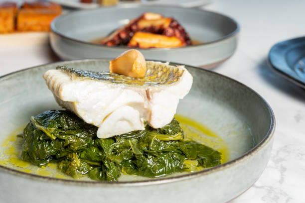 Close-up grilled sea bass steak over spinach served with sauce on grey plate stock photo