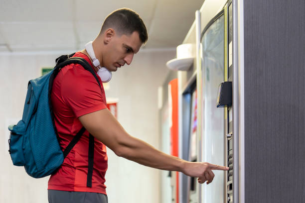 спортсмен в тренажерном зале употребляет напитки из автомата по продаже продуктов питания - vending machine фотографии стоковые фото и изображения