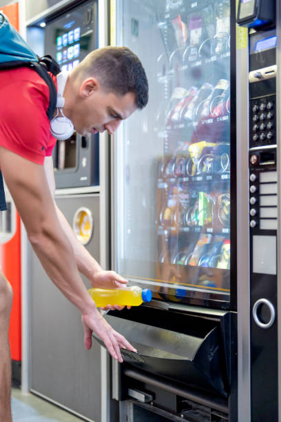 istock Athlete in gym consuming drink from food vending machine 1454015225