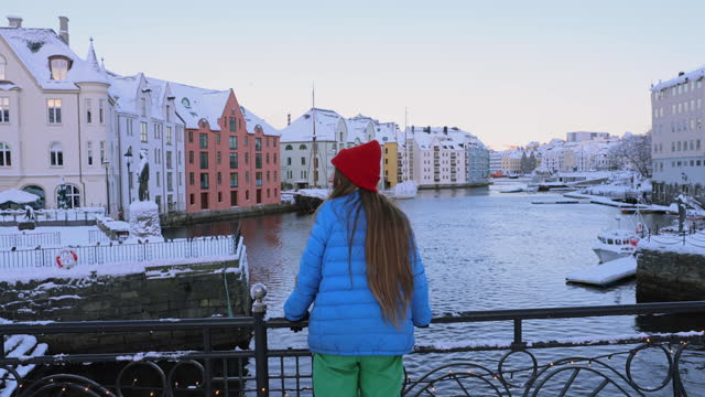 Rear view of woman contemplating a view of Alesund city in snow in Norway