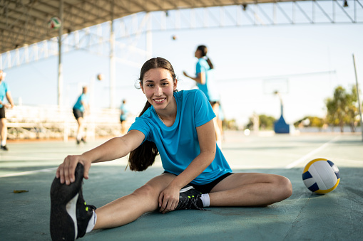 Portrait of female volleyball player stretching at the volleyball court