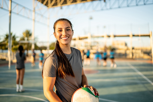 istock Portrait of female volleyball player holding a volleyball ball at sports court 1454026690