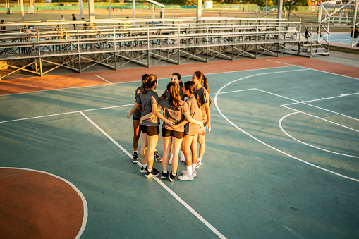 Cute teenage girls, smiling and embracing after basketball match, happy after winning the game leaving the sport field