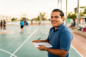 Portrait of young coach man holding a note pad at sports court
