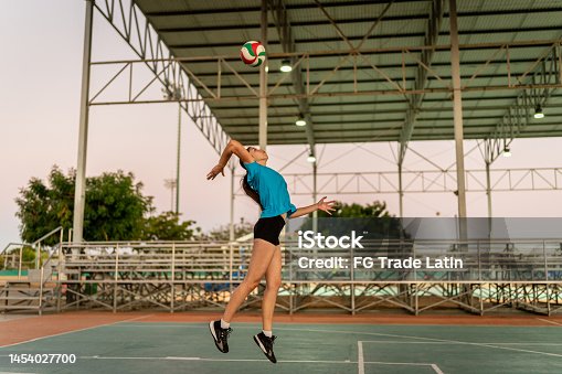 istock Female volleyball player serving the ball during game at sports court 1454027700