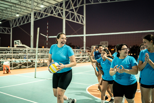 Female volleyball talking after finish of training or celebrating victory after game at sports court