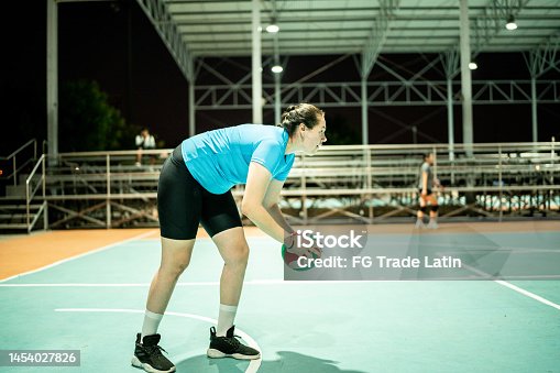 istock Female volleyball player getting ready to serving the ball during game at sports court 1454027826