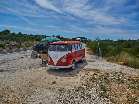 Primosten, Croatia - 06 27 2015: old vintage VW split window micro bus in red and white on the side of the road at the mediterranean coast